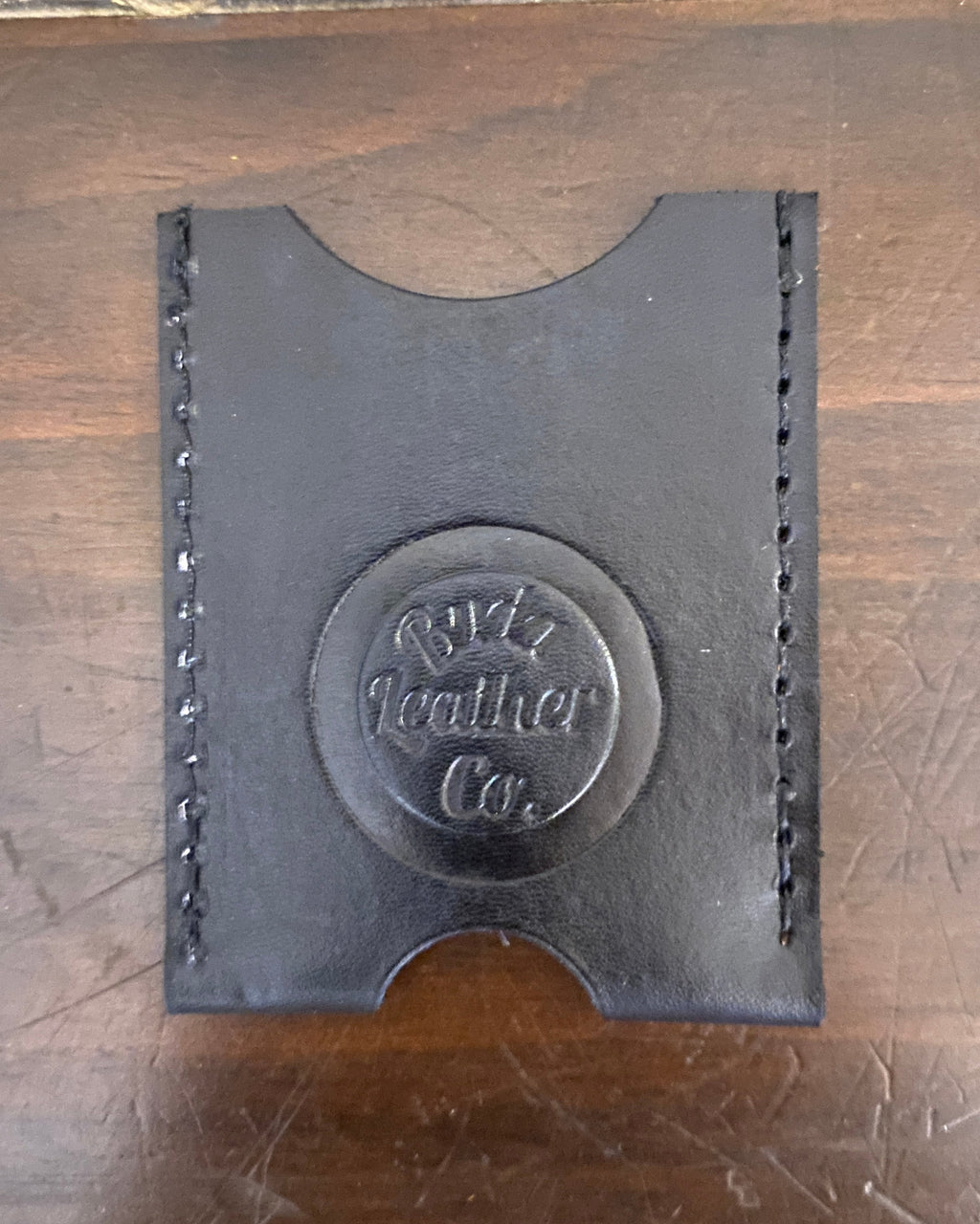 Buda Leather Co. handmade slim  black leather card wallet with stamped logo, measuring 3.5 inches by 2.5 inches.