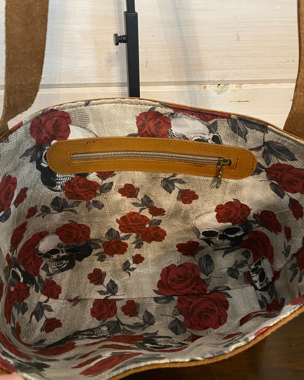 Close-up of the inside of a fabric bag or basket with a red rose floral print on a light beige background and a tan zipper pocket.