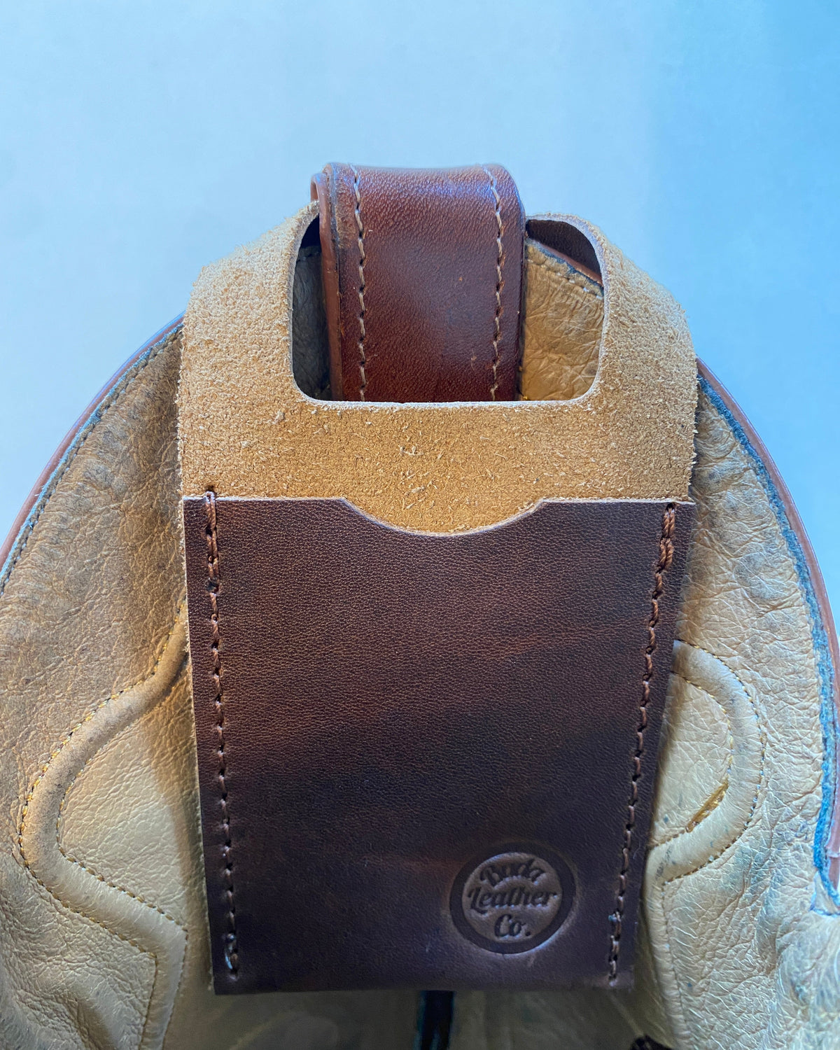 Brown leather boot wallet attached to a cowboy boot on a light blue background