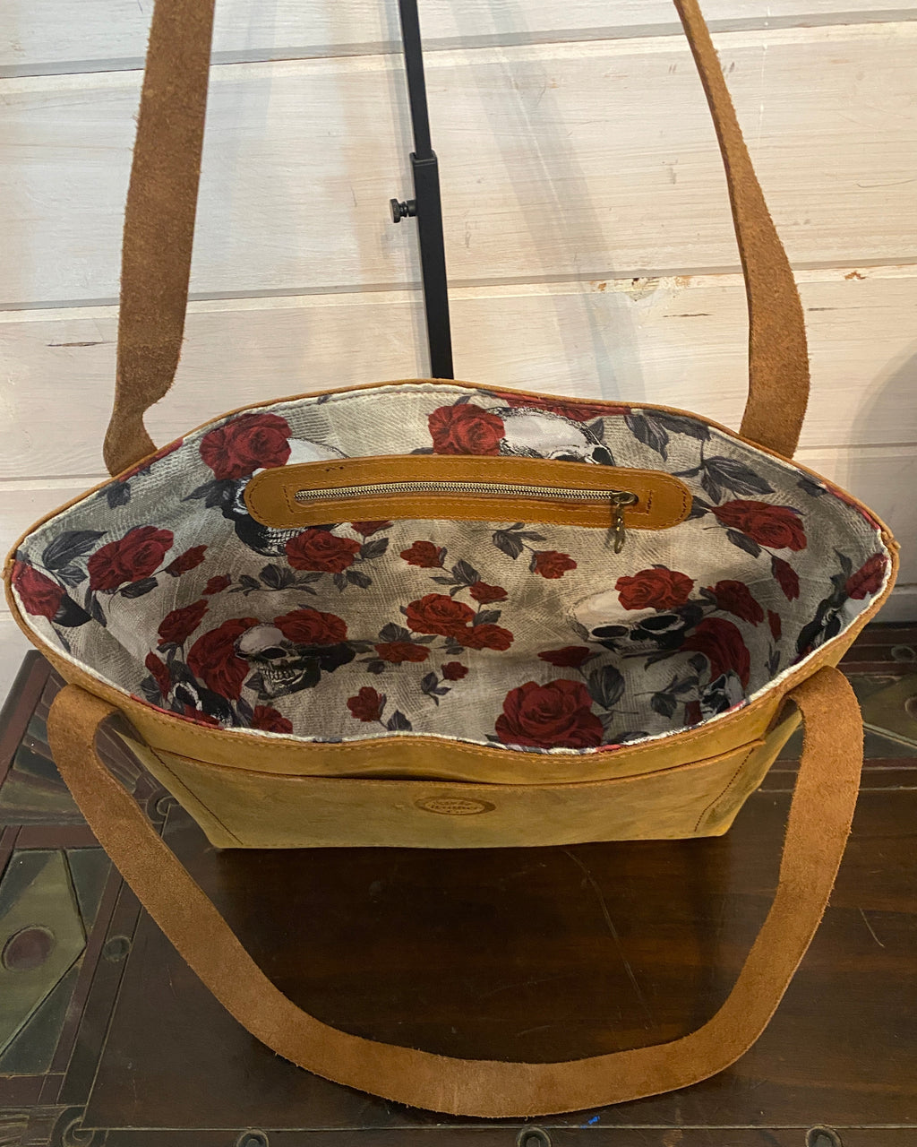 A handmade tote bag with tan leather handles and trim, featuring a cream fabric lining with a red and black floral rose pattern.